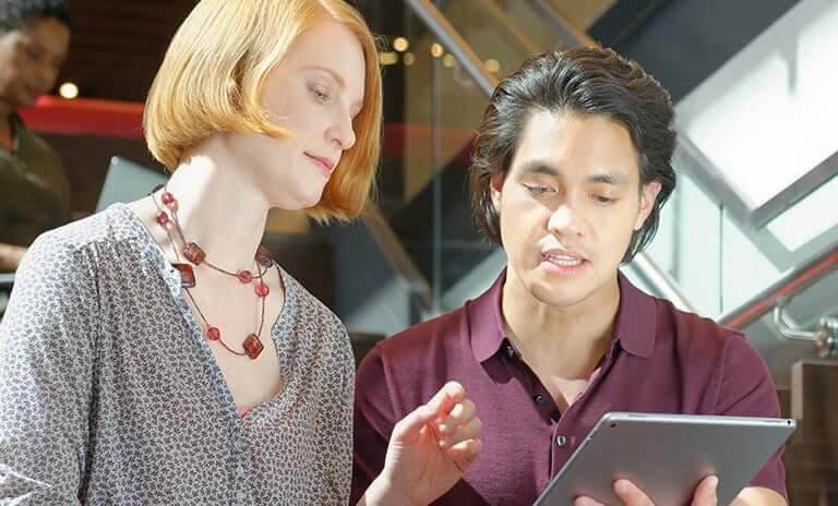 male and female employee consulting over a tablet